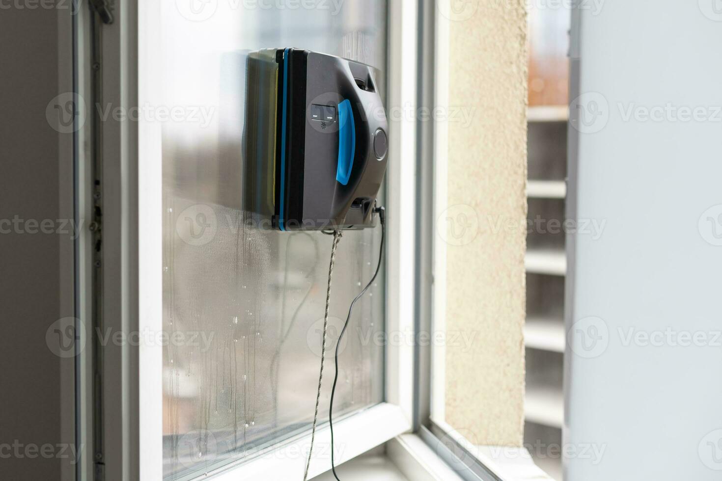 Crop of smart vacuum cleaner washing windows. Home appliance and technology concept photo