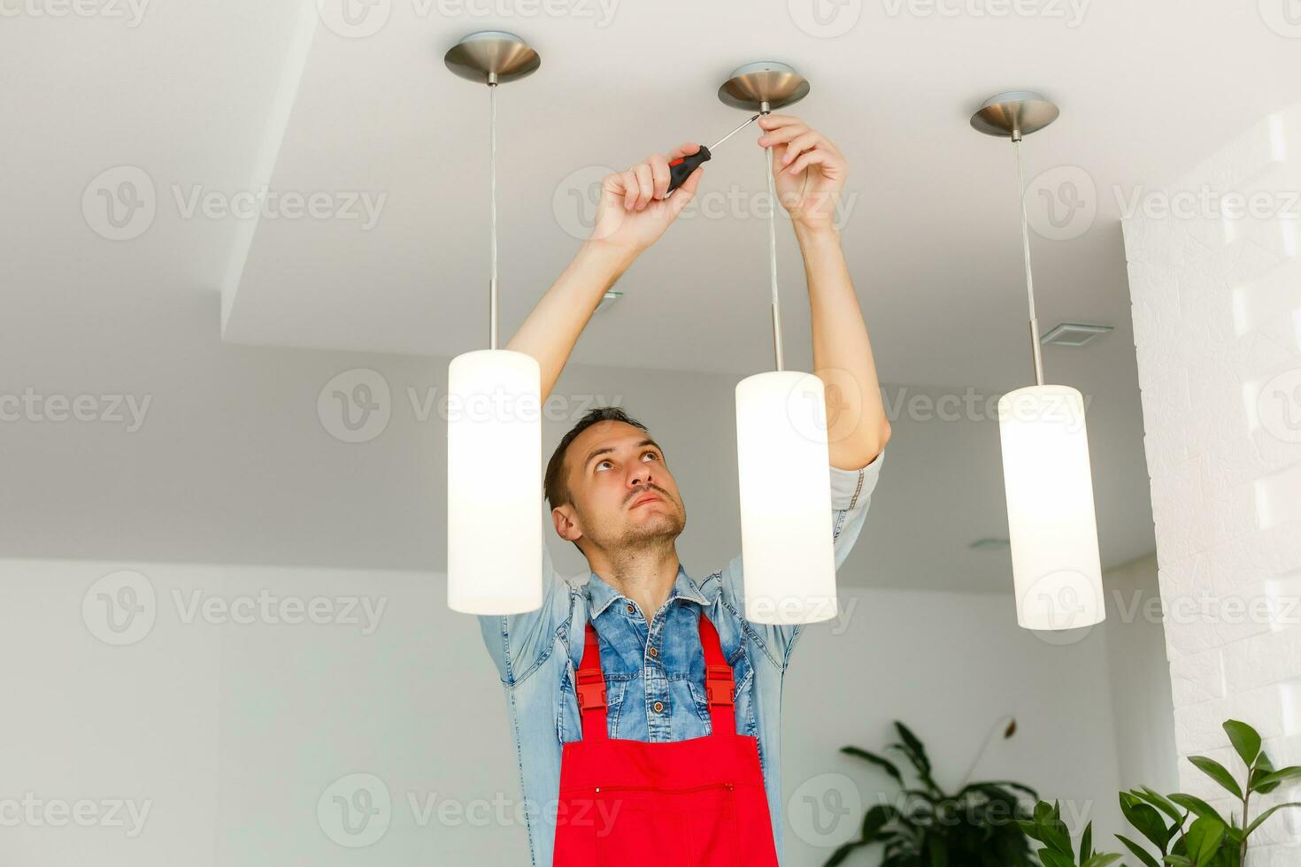 Electrician man worker installing ceiling lamp photo