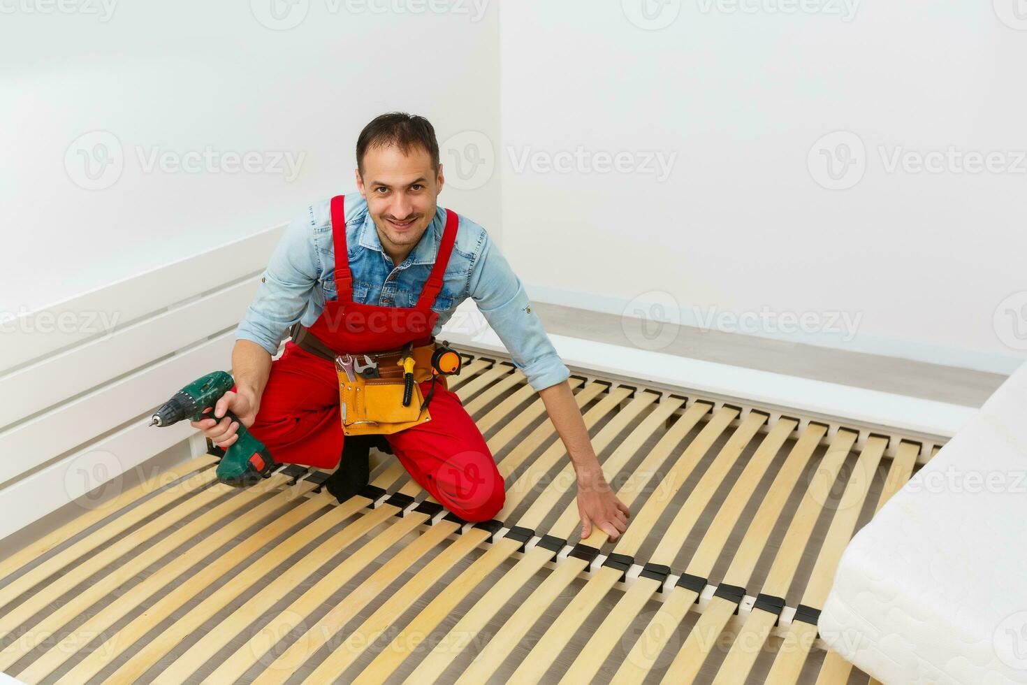 Man's hands working with a hex key. Assembling furniture. Wooden plank of a bed. Close up. photo