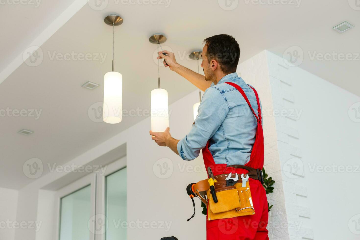 Electrician man worker installing ceiling lamp photo