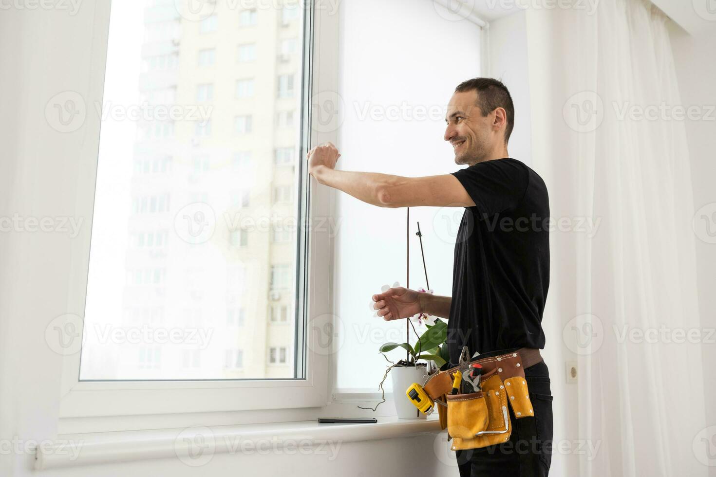 Handyman using a cordless screwdriver to install a window handle. Qualified worker services, home repair and renovation. photo