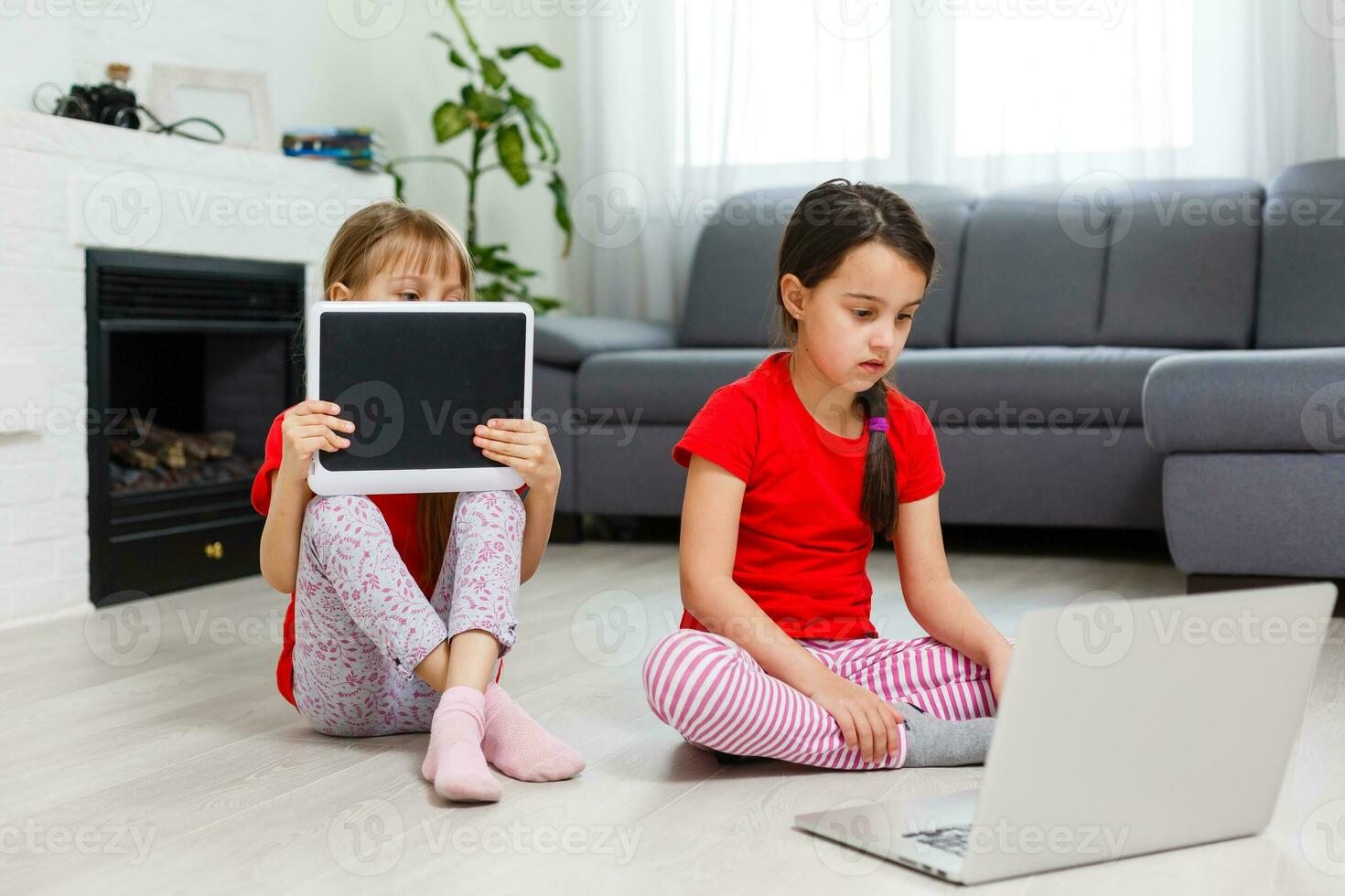 Little girls playing on a tablet computing device sitting on the floor photo