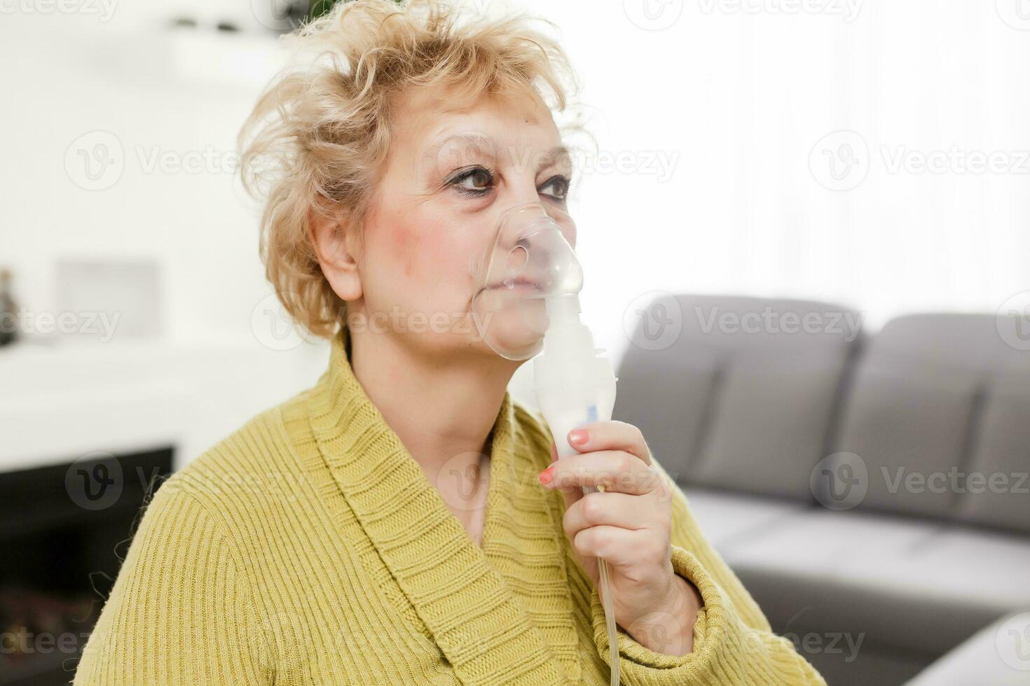 Close-up portrait of a senior woman in a medical mask. The use of the nebulizer. photo