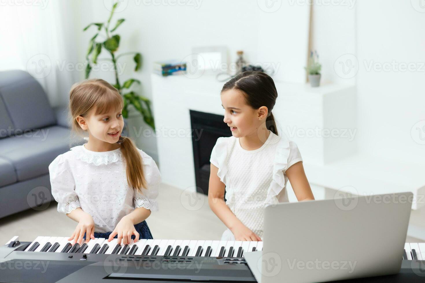 Home piano lesson. two girls practice sheet music on one musical instrument. Family concept. The idea of activities for children during quarantine. photo