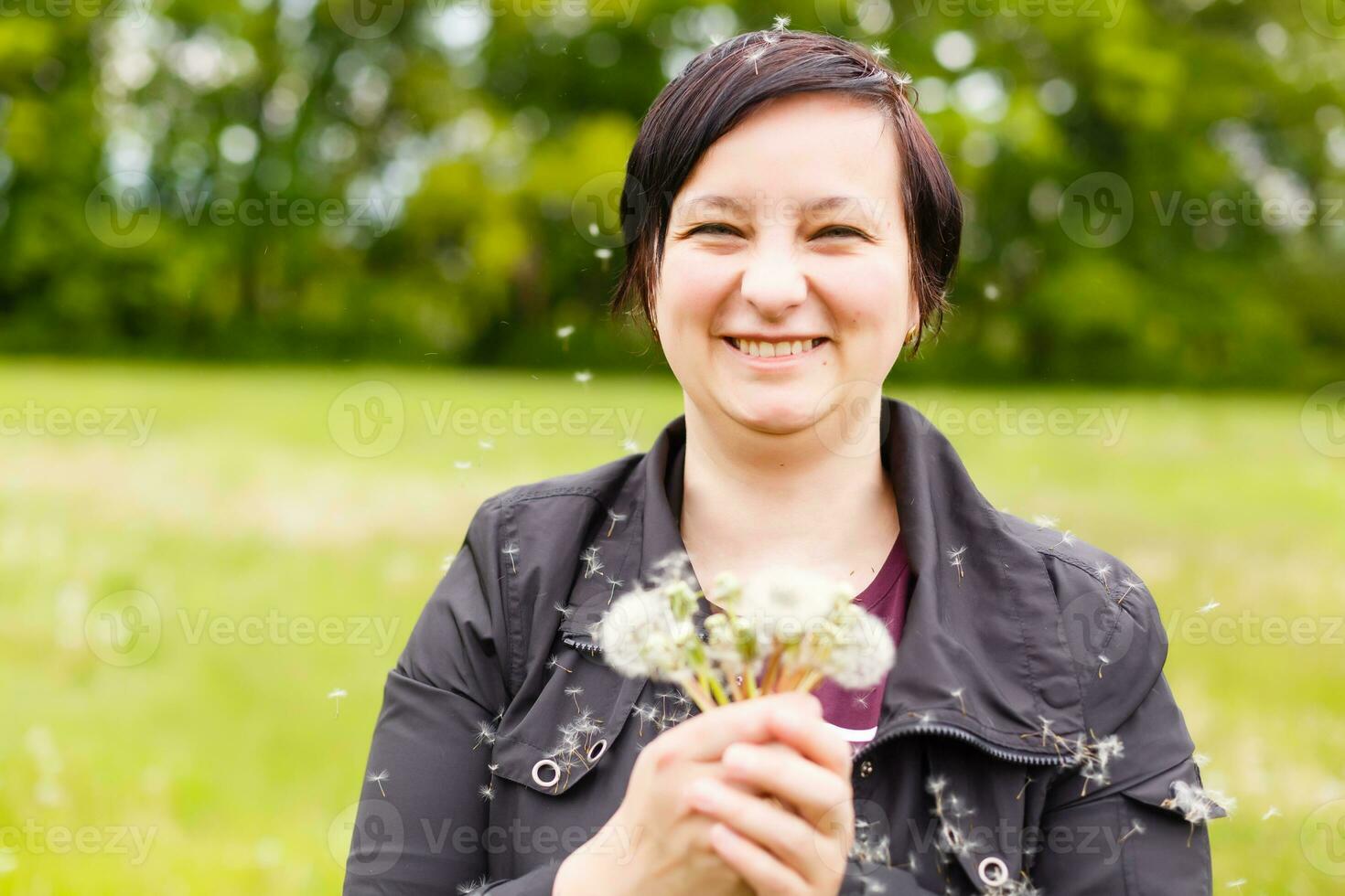 Girl blowing on white dandelion in the forest photo