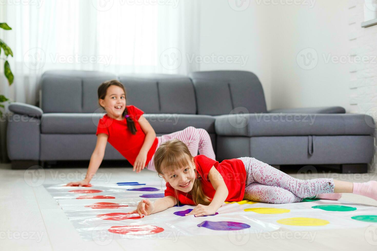 Two happy girls in children's clothes enthusiastically play on the floor. photo