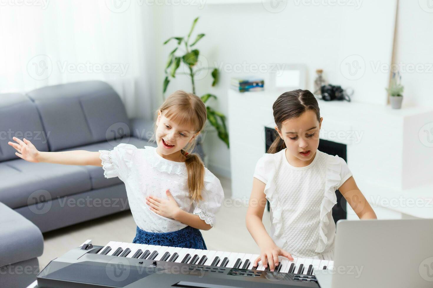 Home piano lesson. two girls practice sheet music on one musical instrument. Family concept. The idea of activities for children during quarantine. photo