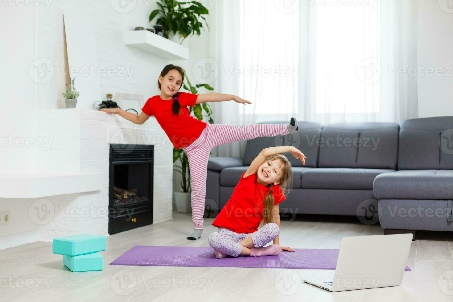 two little girls practicing yoga, stretching, fitness by video on notebook. Distant online education training, aerobic at home. Healthy lifestyle, coronavirus, stay home. Kids sport home quarantine. photo