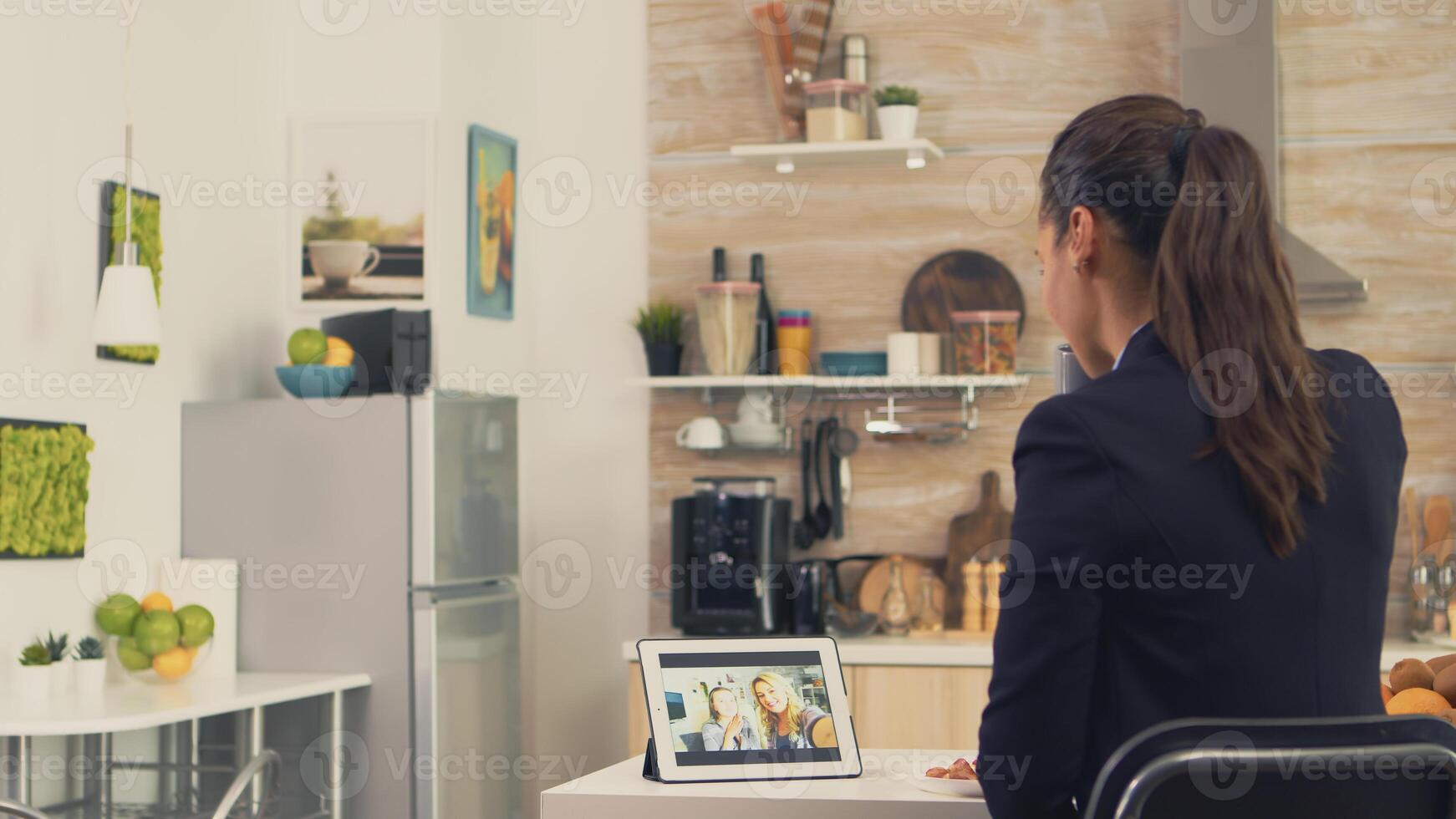 Business woman during a video call with sister while eating breakfast. Using modern online internet web technology to chat via webcam videoconference app with relatives, family, friends and coworkers photo