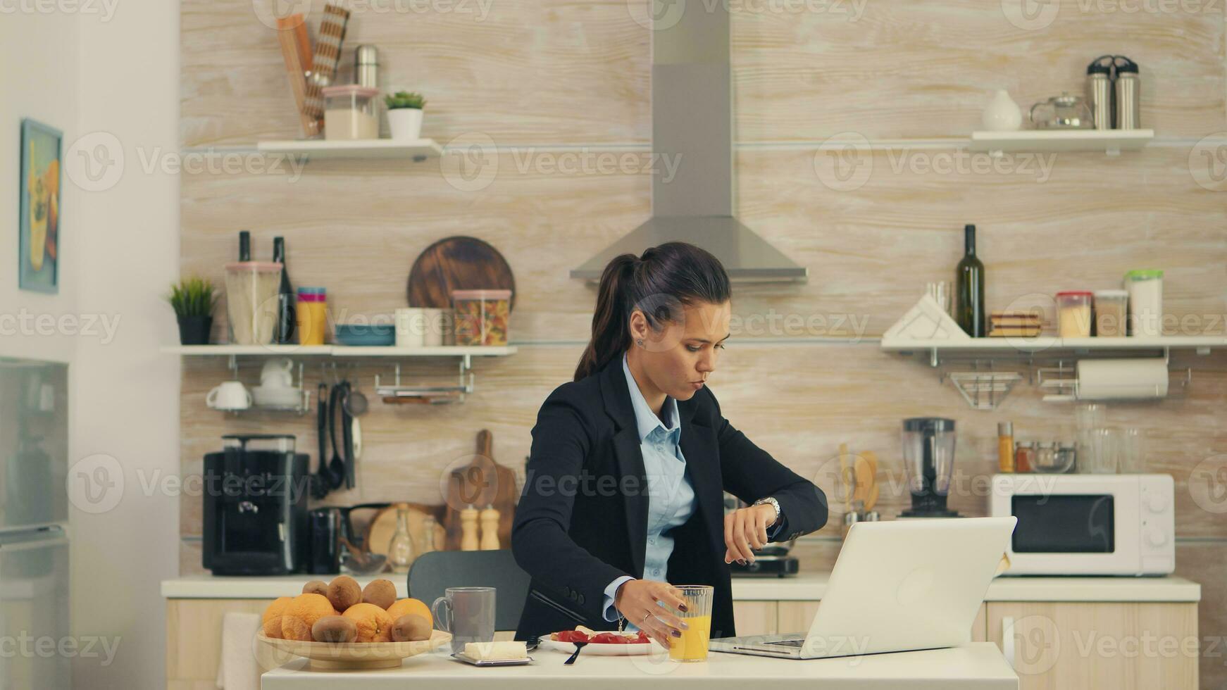 Freelancer woman late at the office while eating breakfast. Young freelancer working around the clock to meet her goals, stressful way of life, hurry, late for work, always on the run photo