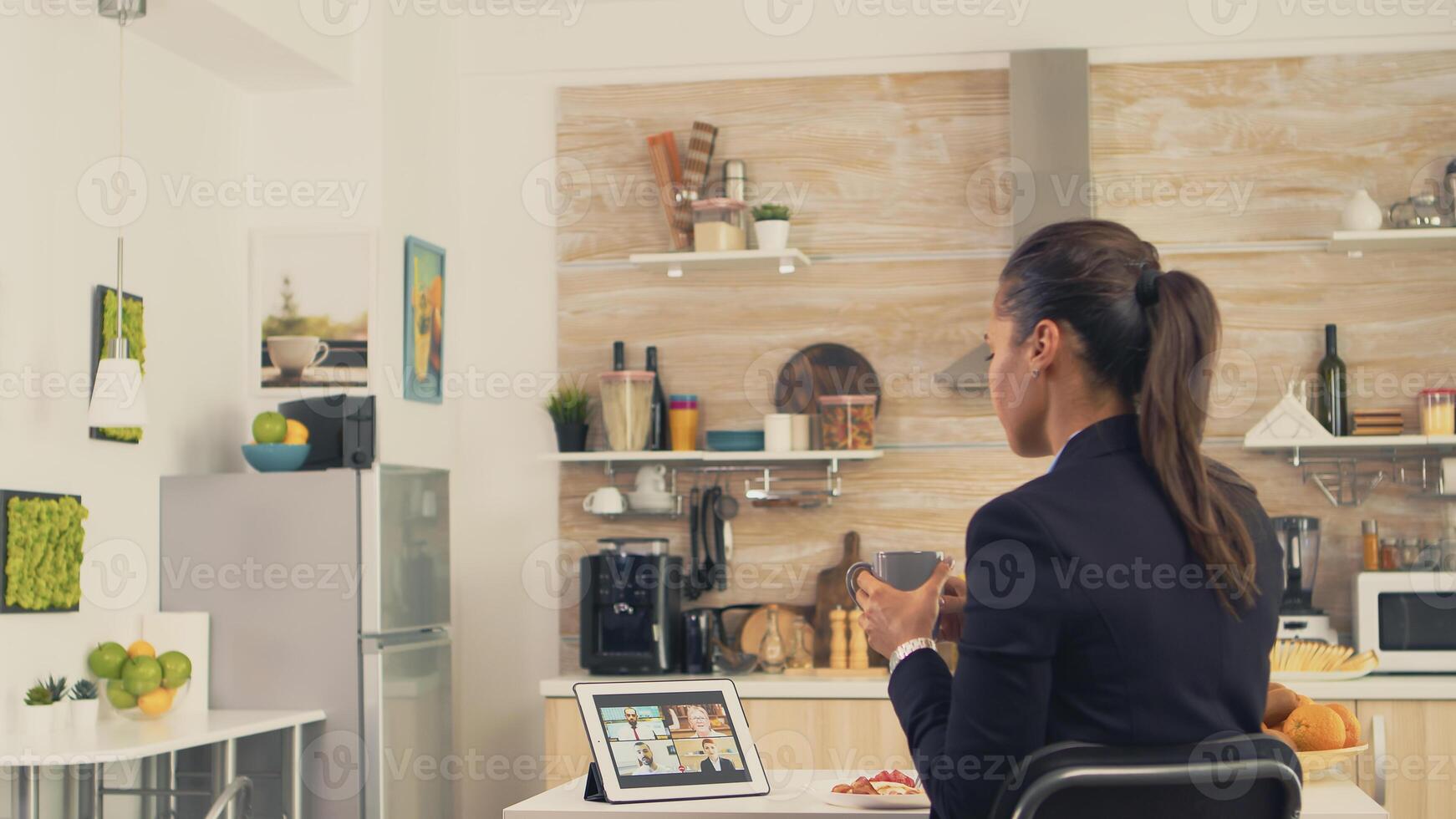 negocio mujer durante un vídeo llamada con amigos mientras comiendo desayuno antes de dejando a el oficina. utilizando moderno en línea Internet web tecnología a charla vía cámara web video conferencia aplicación con parientes, familia, amigos y compañeros de trabajo foto