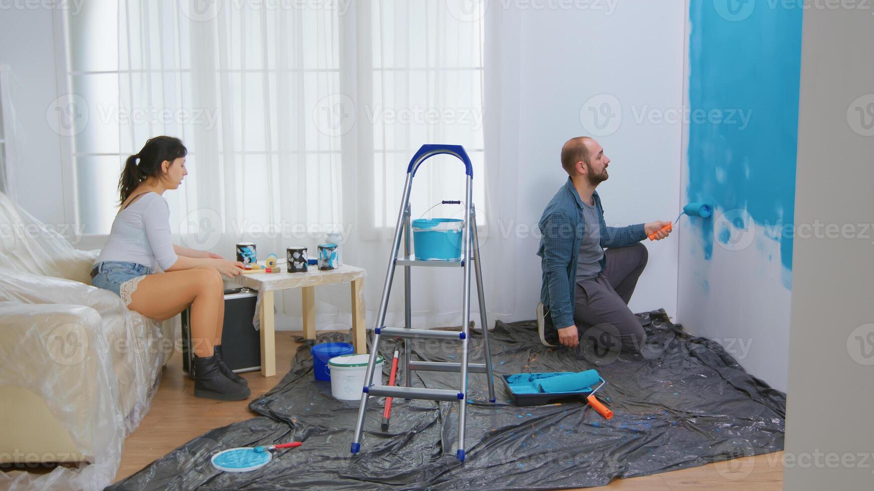 Couple conversation and home renovation. Roller brush dipped in blue paint. Apartment redecoration and home construction while renovating and improving. Repair and decorating. photo