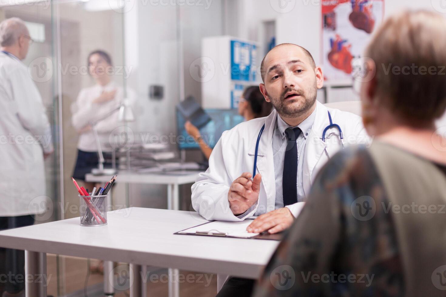 Doctor explaining illness diagnosis to senior woman during medical consultation. Mature physician discussing sickness treatment with young woman. photo