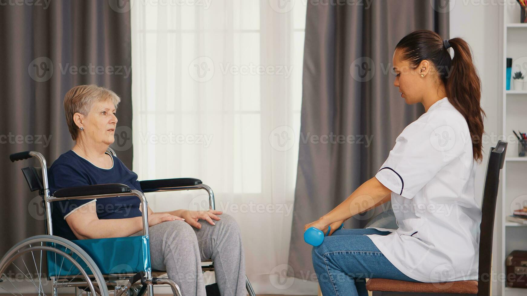 Senior woman in wheelchair doing physical rehabilitation with with doctor. Training, sport, recovery and lifting, old person retirement home, healthcare nursing, health support, social assistance, doctor and home service photo