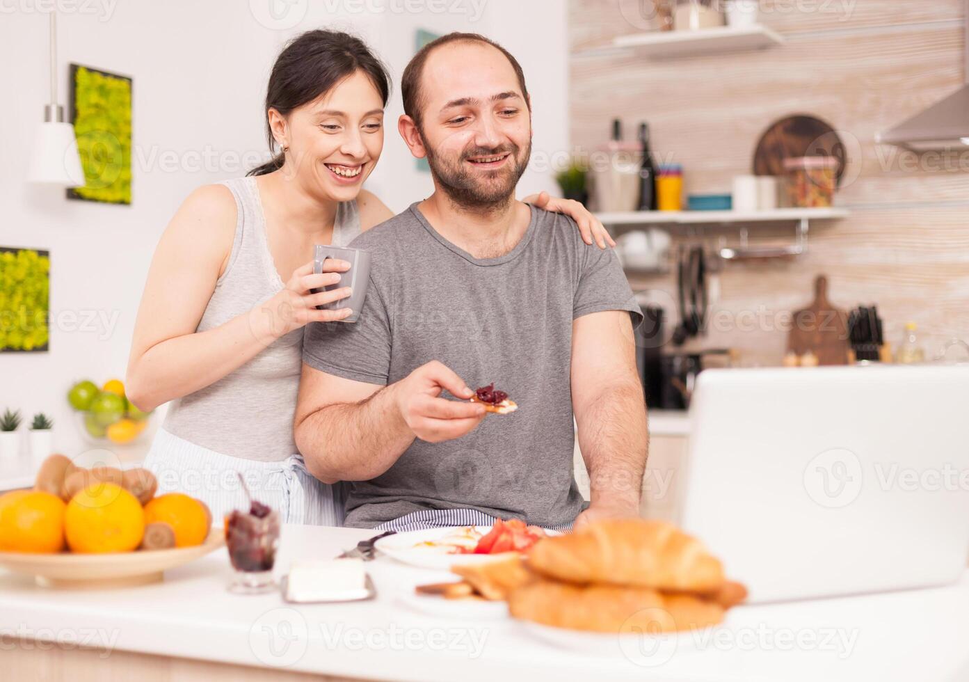 Couple talking online with family on a video call during breakfast. Videoconference in the morning, using online web internet technology, talking and communicating with relatives photo