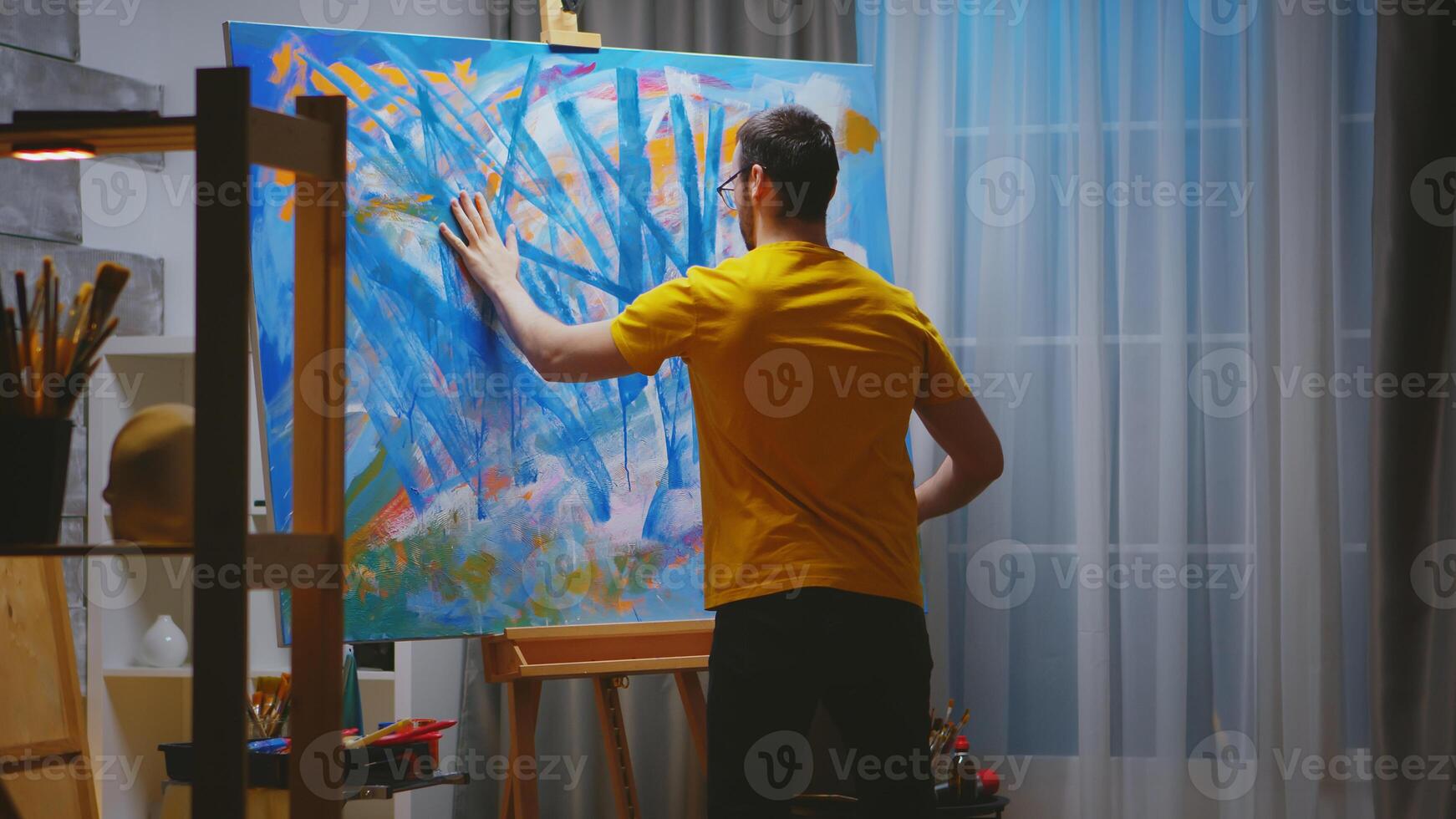 Impressionism painter in art studio painting with fingers on large canvas. photo