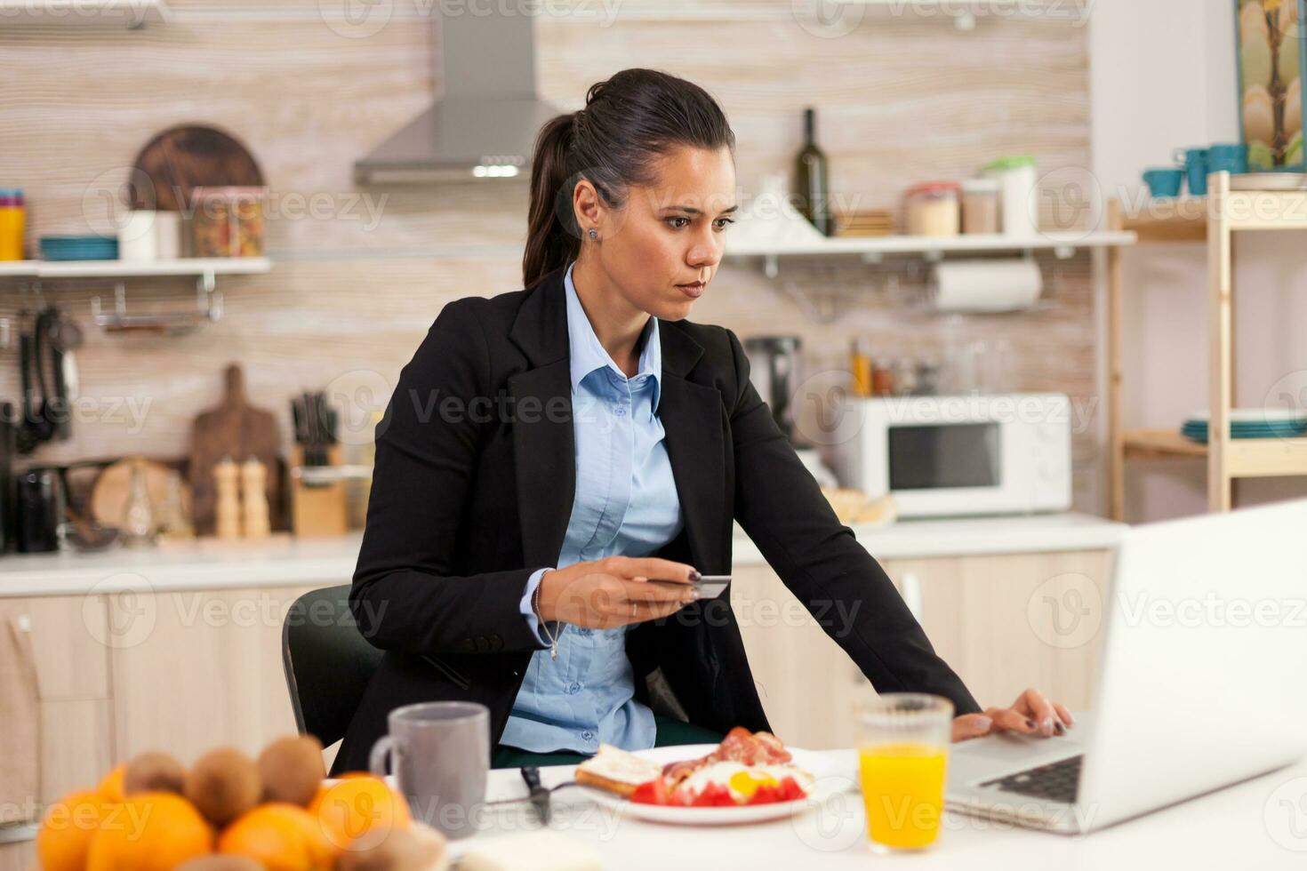 Woman using credit card in the morning before going to work. Shopping online for goods and clothes, using modern technology in every day life, making payments via internet. photo