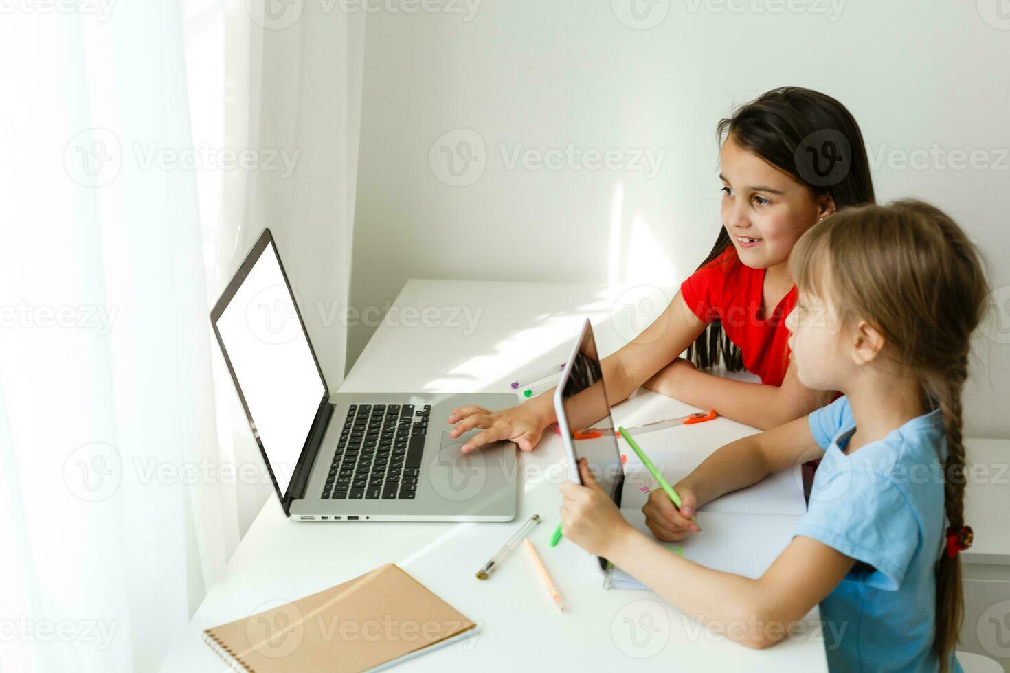 Cool online school. Kids studying online at home using a laptop. Cheerful young little girls using laptop computer studying through online e-learning system. Distance or remote learning photo