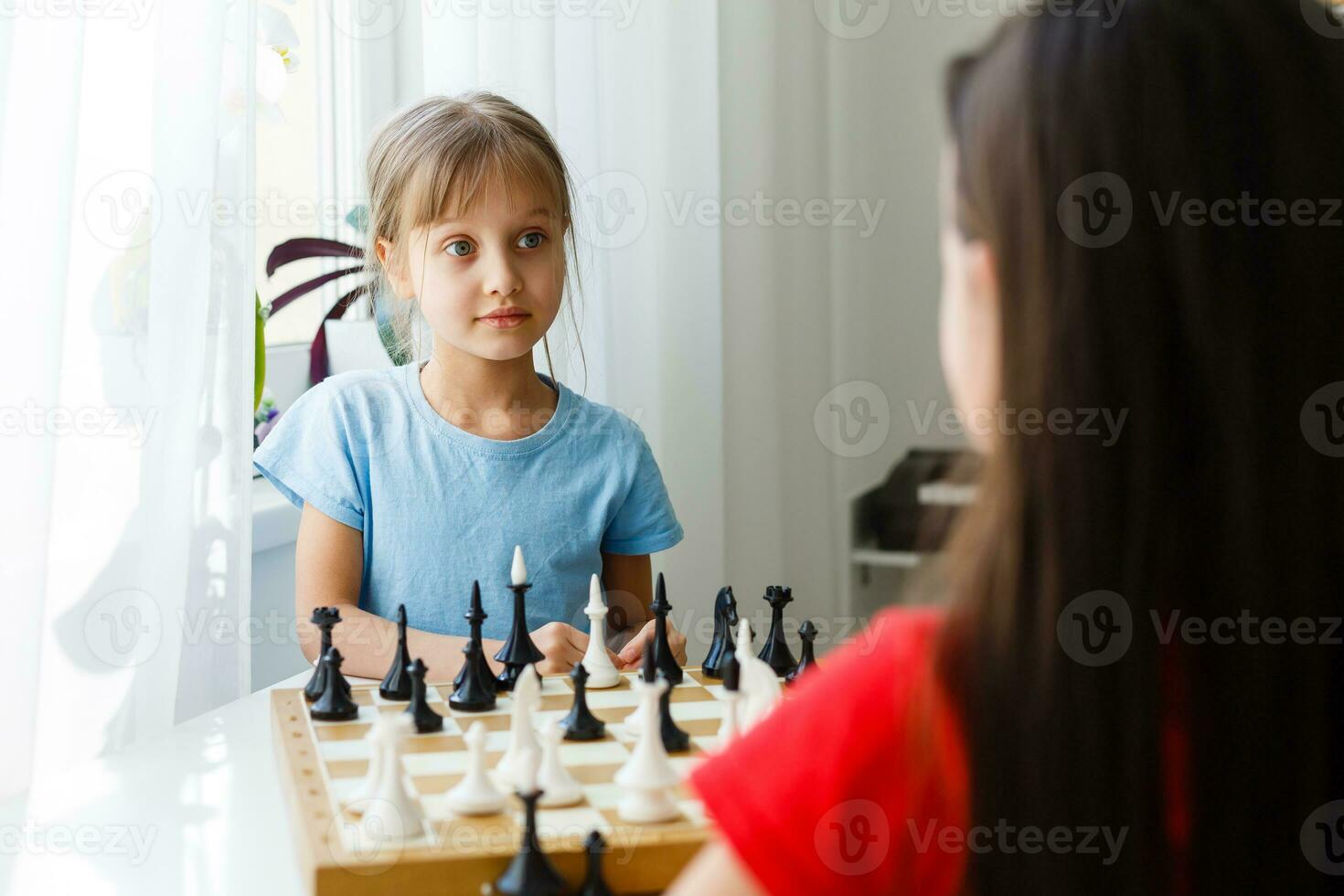 Two cute children playing chess at home photo