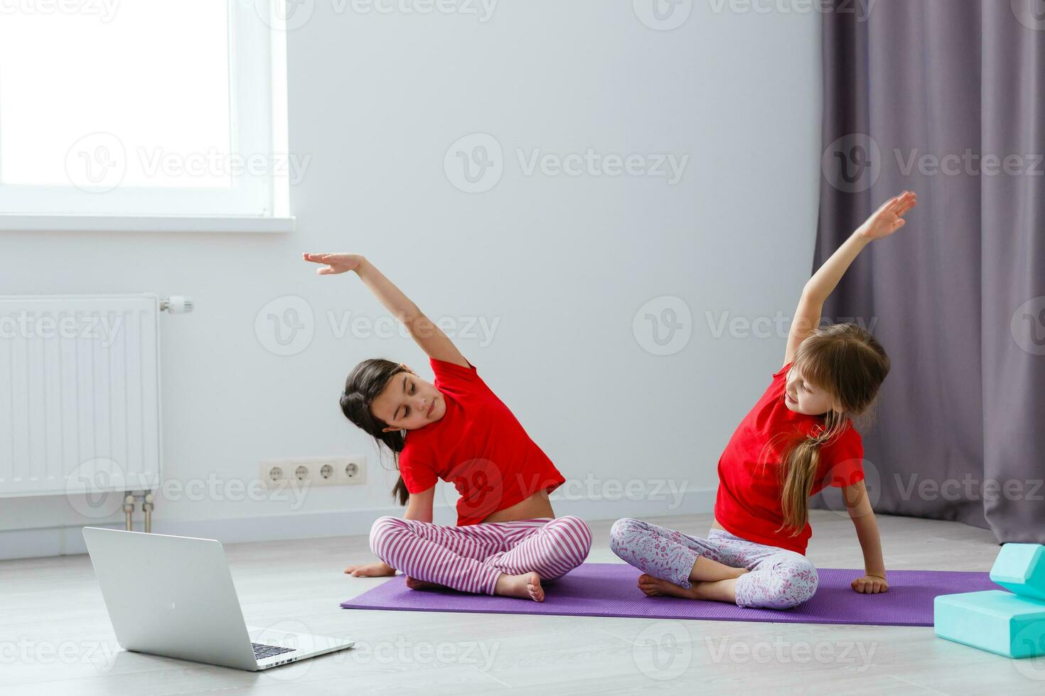 two little girls practicing yoga, stretching, fitness by video on notebook. Distant online education training, aerobic at home. Healthy lifestyle, coronavirus, stay home. Kids sport home quarantine. photo