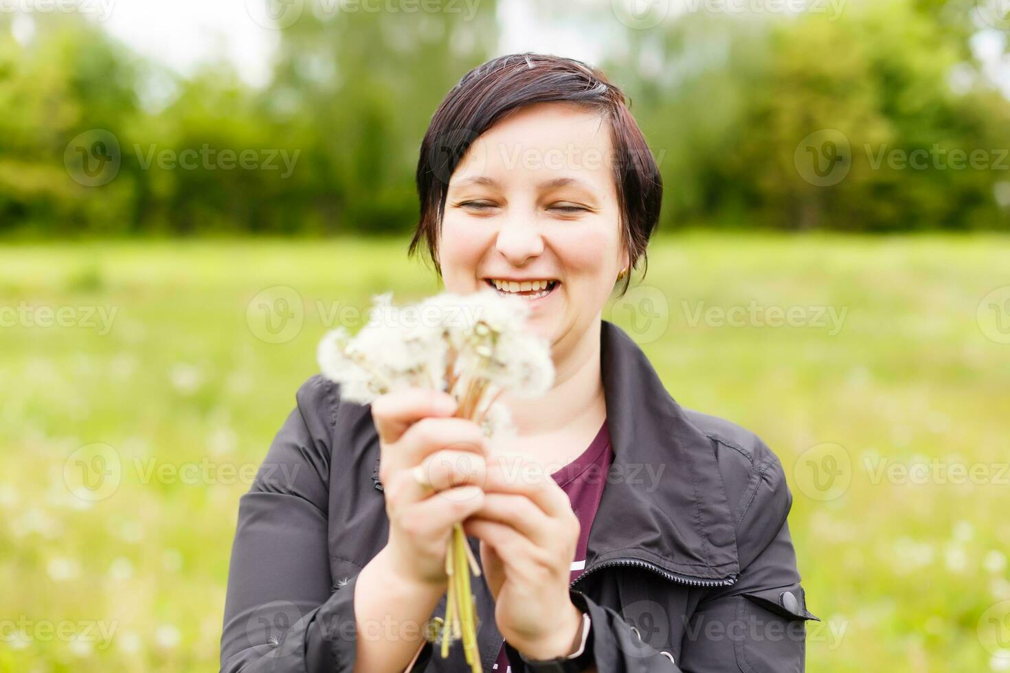 Girl blowing on white dandelion in the forest photo