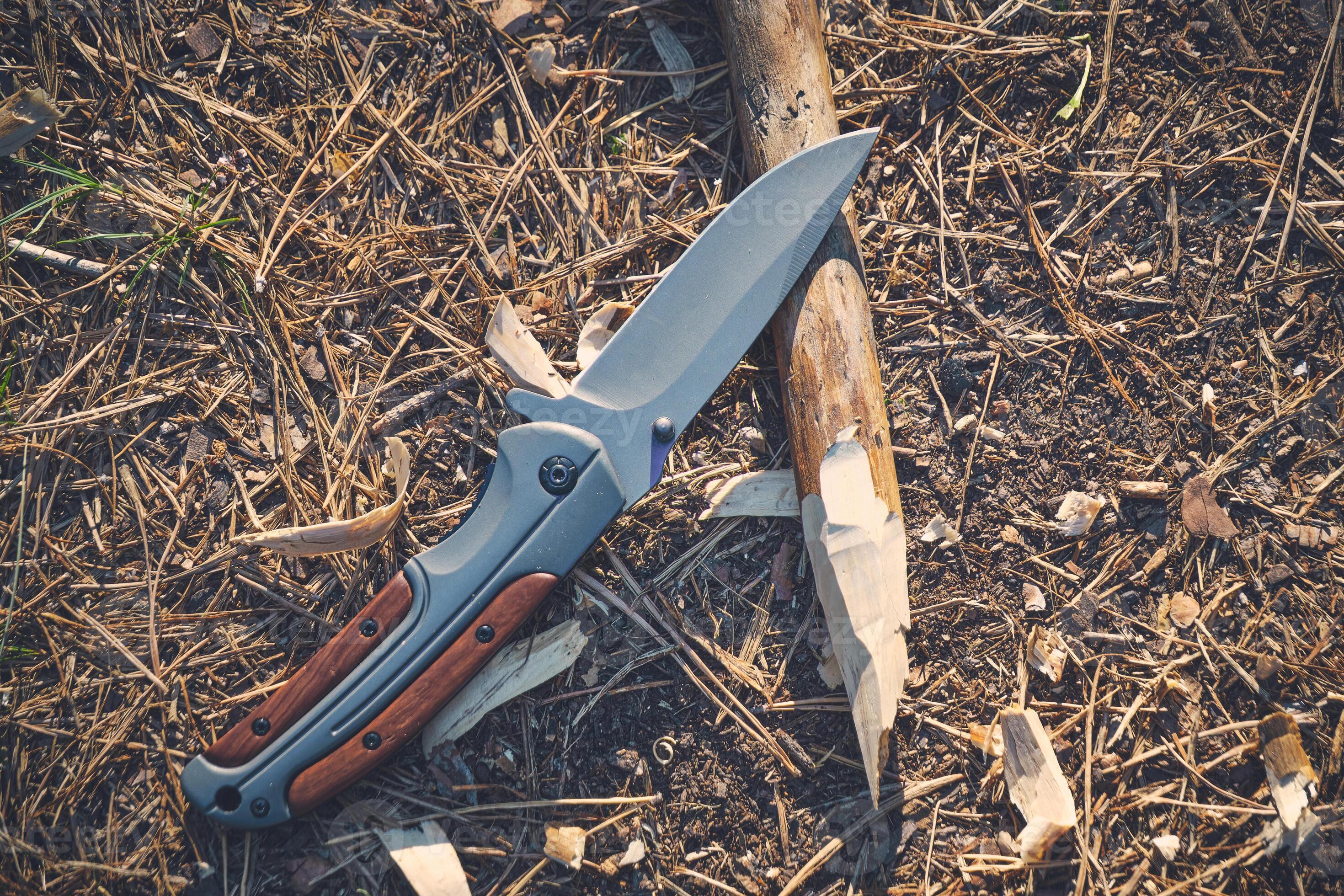Folding hunting knife for survival and sharpened peg lie ground