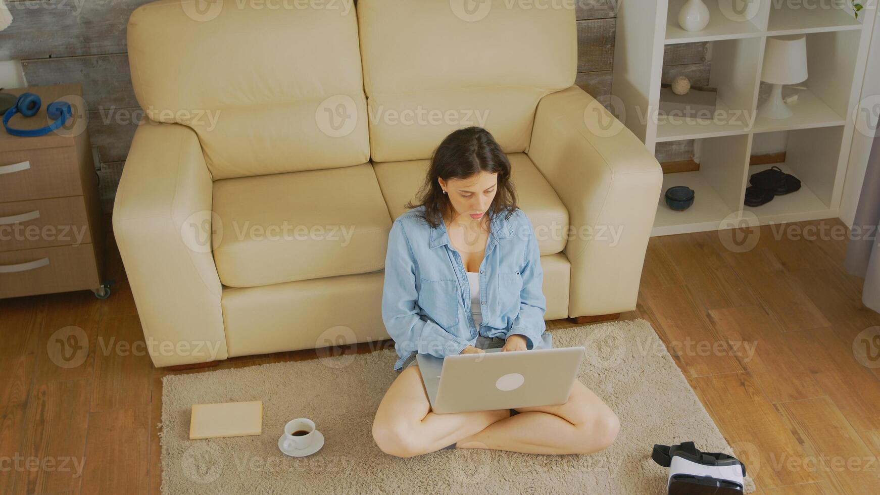Top down view of caucasian woman typing an email sitting on the floor of her cozy bright home photo