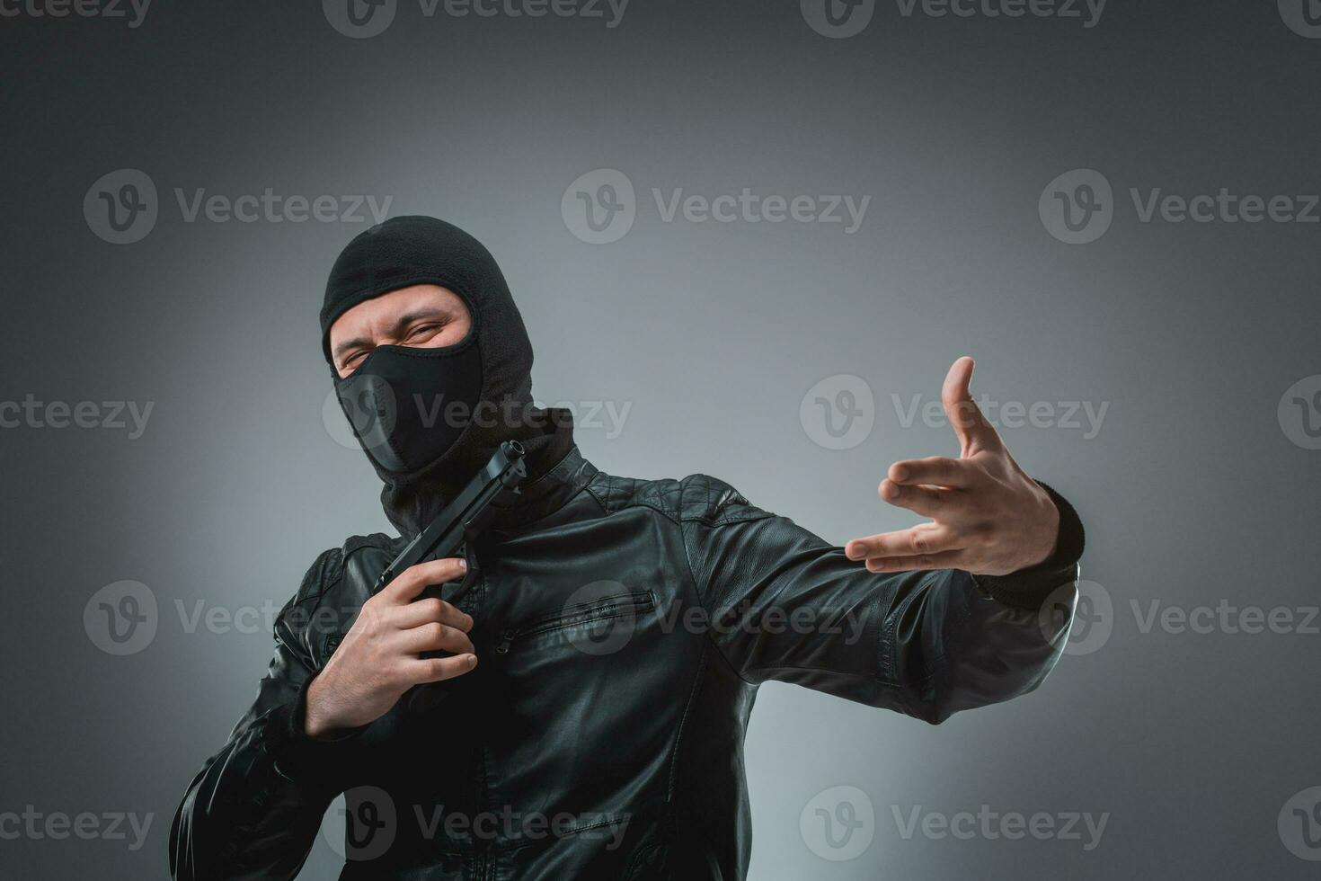 Robber with a gun, studio shot photo