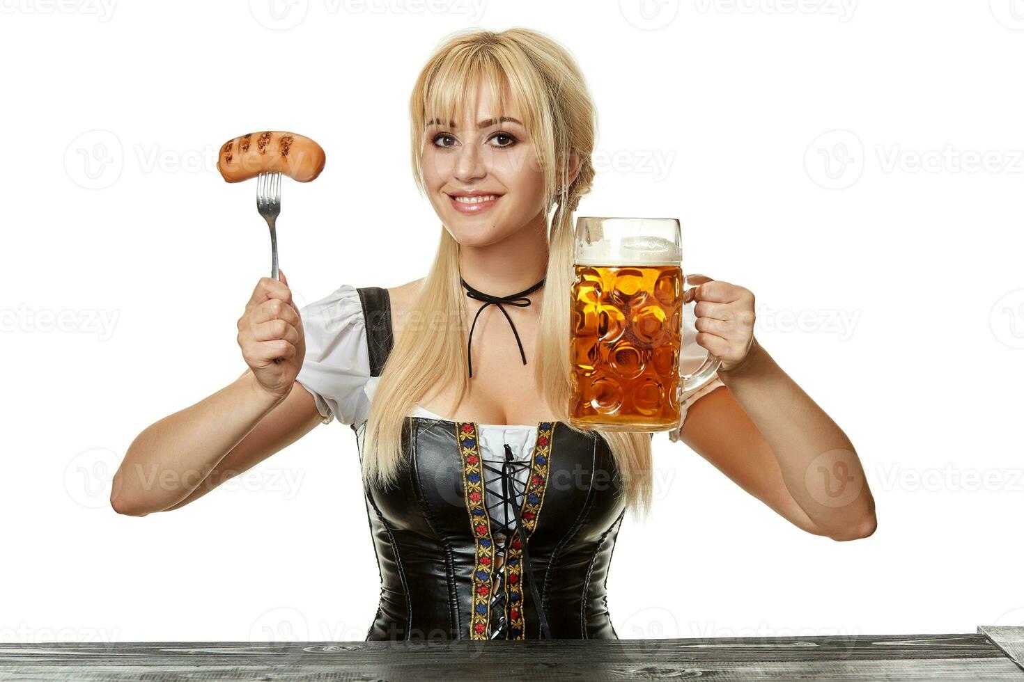 Young bavarian woman in dirndl sitting at table with beer on white background photo