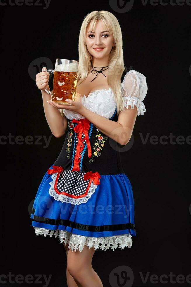 Young sexy woman wearing a dirndl with beer mug on black background. photo