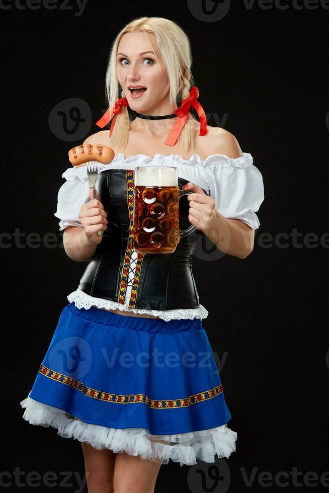 Young sexy woman wearing a dirndl with beer mug on black background. photo