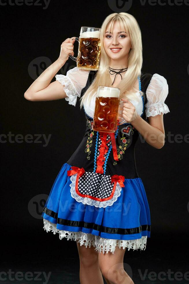 Young sexy woman wearing a dirndl with two beer mugs on black background. photo