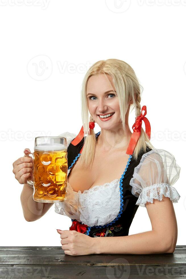Young bavarian woman in dirndl sitting at table with beer on white background photo