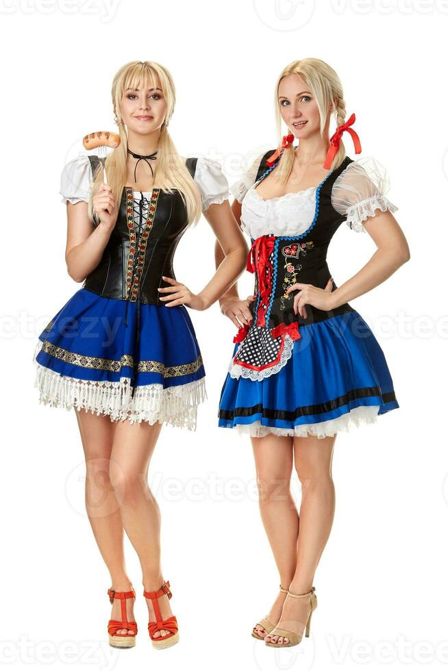 Full length portrait of a two blond womans with traditional costume holding beer glasses isolated on white background. photo