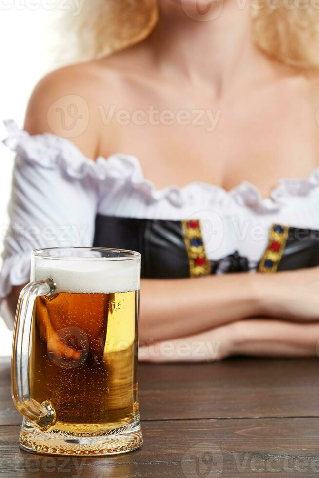 Beautiful young blond girl in traditional costume drinks out of oktoberfest beer stein. photo