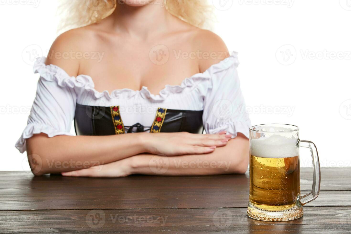 Beautiful young blond girl in traditional costume drinks out of oktoberfest beer stein. photo
