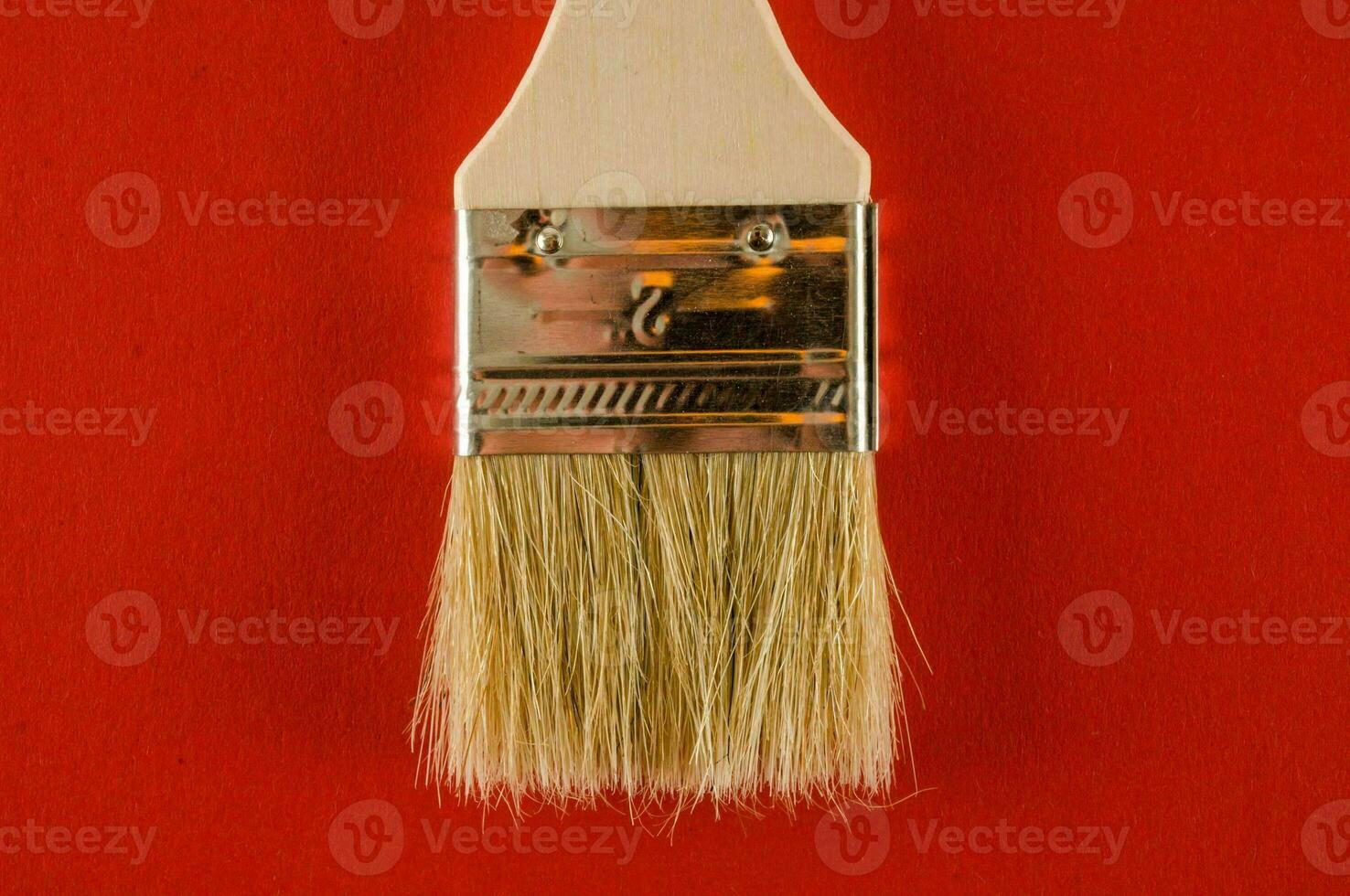 a brush with a wooden handle on a red background photo