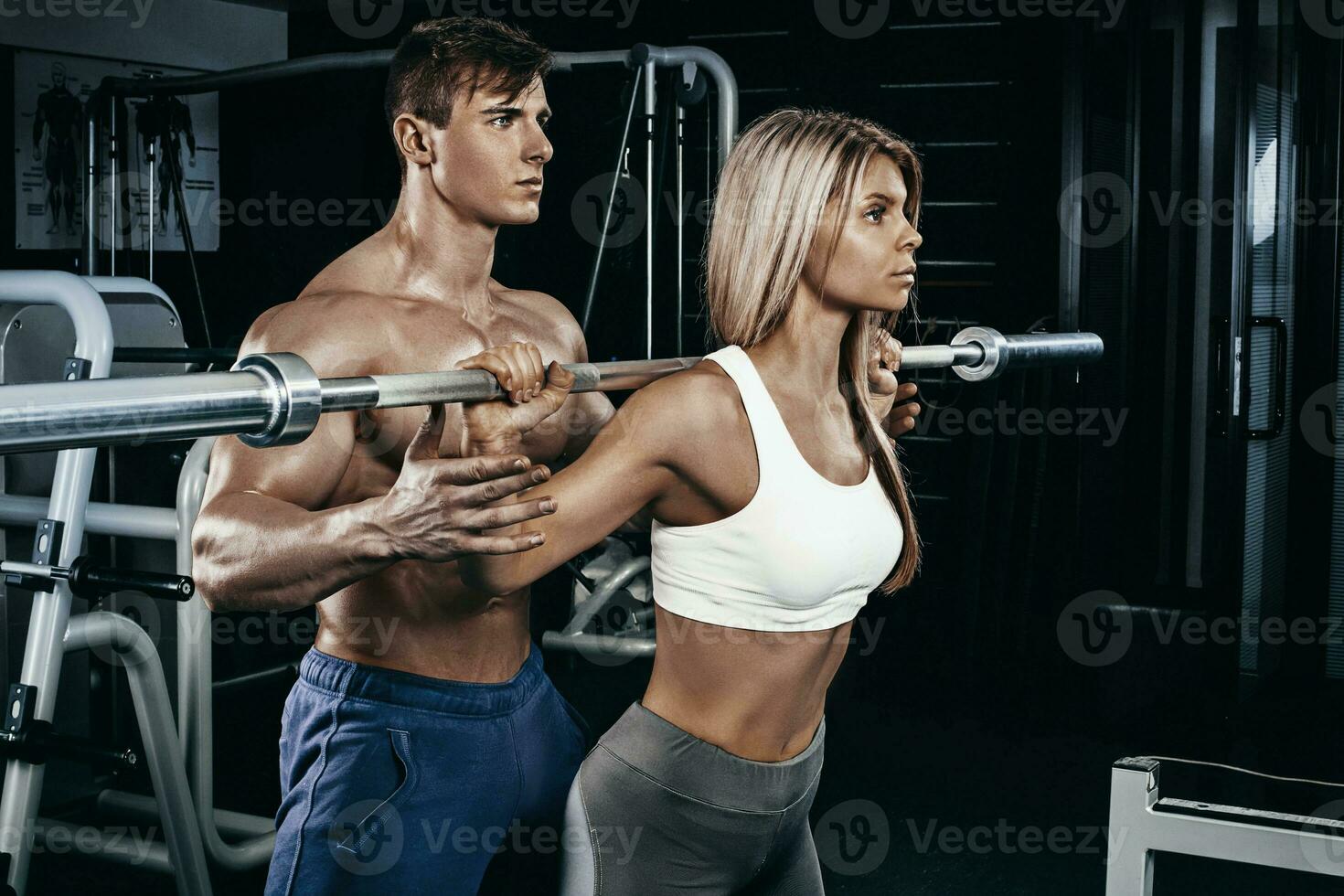Fitness instructor exercising with his client at the gym. photo
