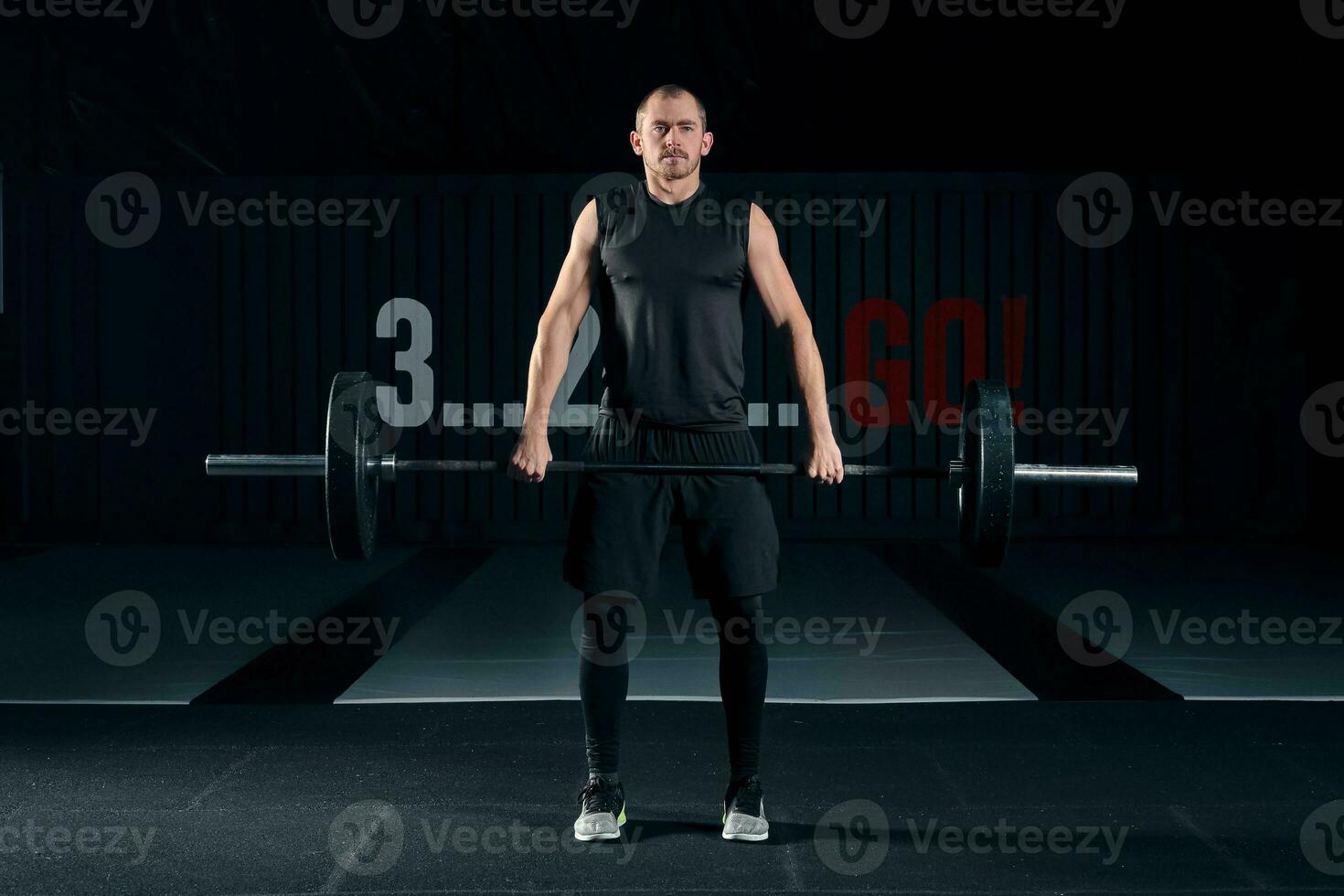 Young man with barbell flexing muscles and making shoulder press lunge in gym photo