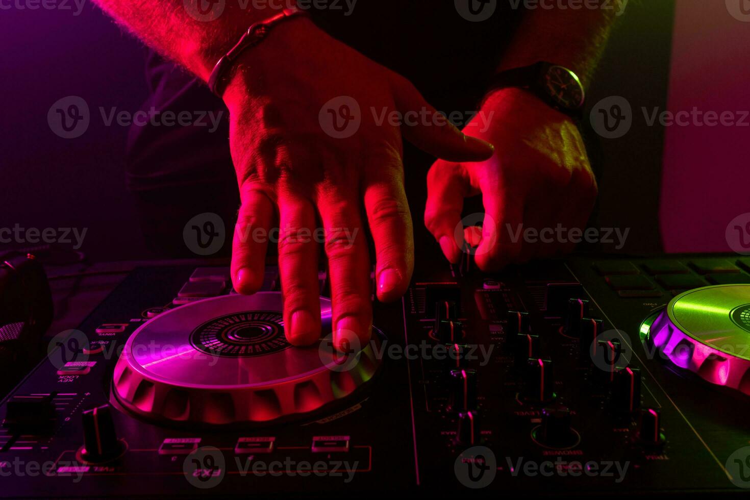 Dj mixing on turntables with color light effects. Soft focus on hand. Close-up. photo