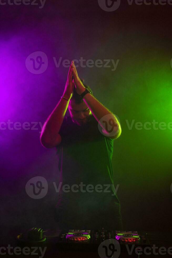 DJ playing music at mixer on colorful foggy background photo