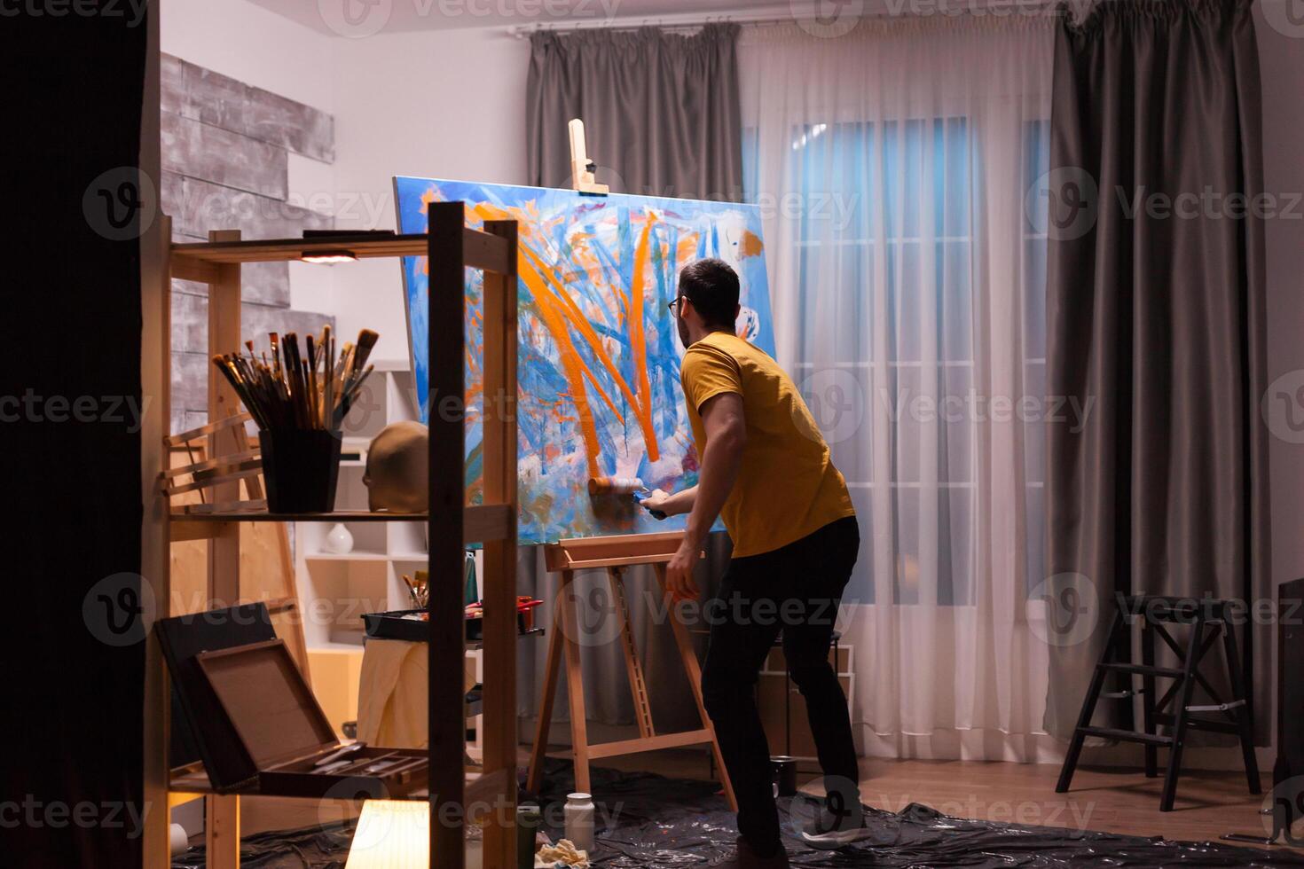 Artist painting on canvas with roller in art workshop. Modern artwork paint on canvas, creative, contemporary and successful fine art artist drawing masterpiece photo