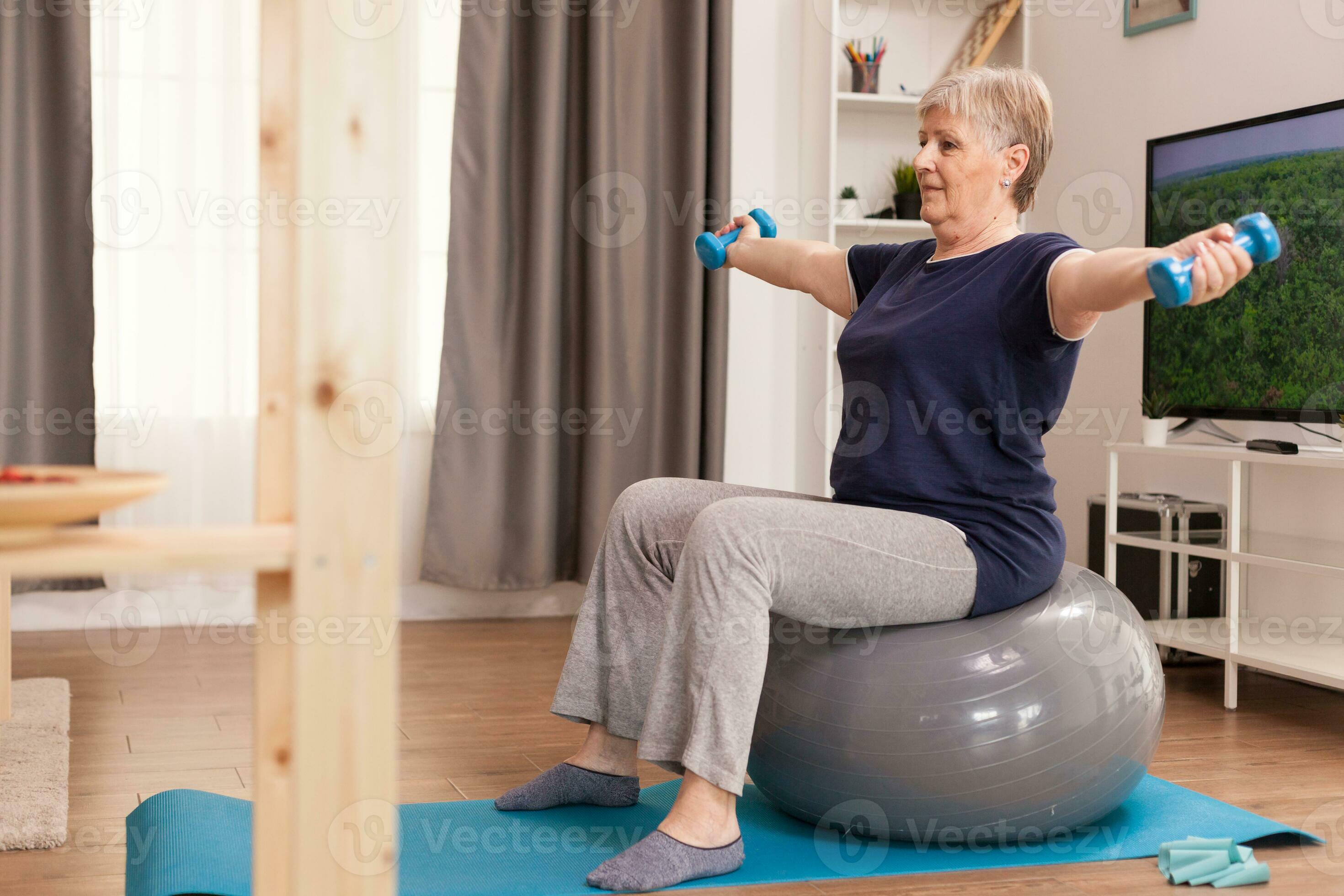 Active grandma using resistance band sitting on yoga mat at home