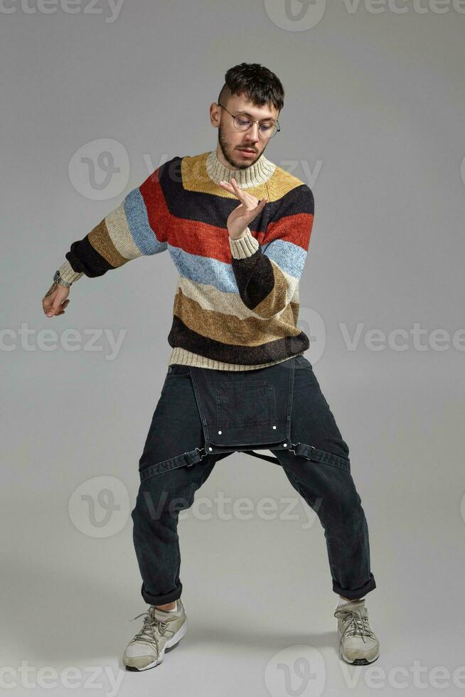 Full-length portrait of a funny guy dancing in studio on a gray background. photo