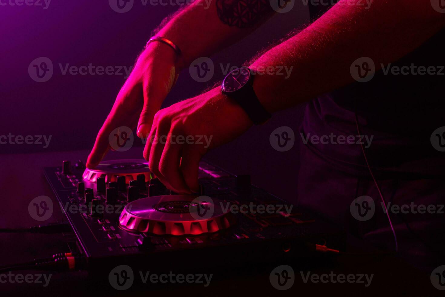 Dj mixing on turntables with color light effects. Soft focus on hand. Close-up. photo