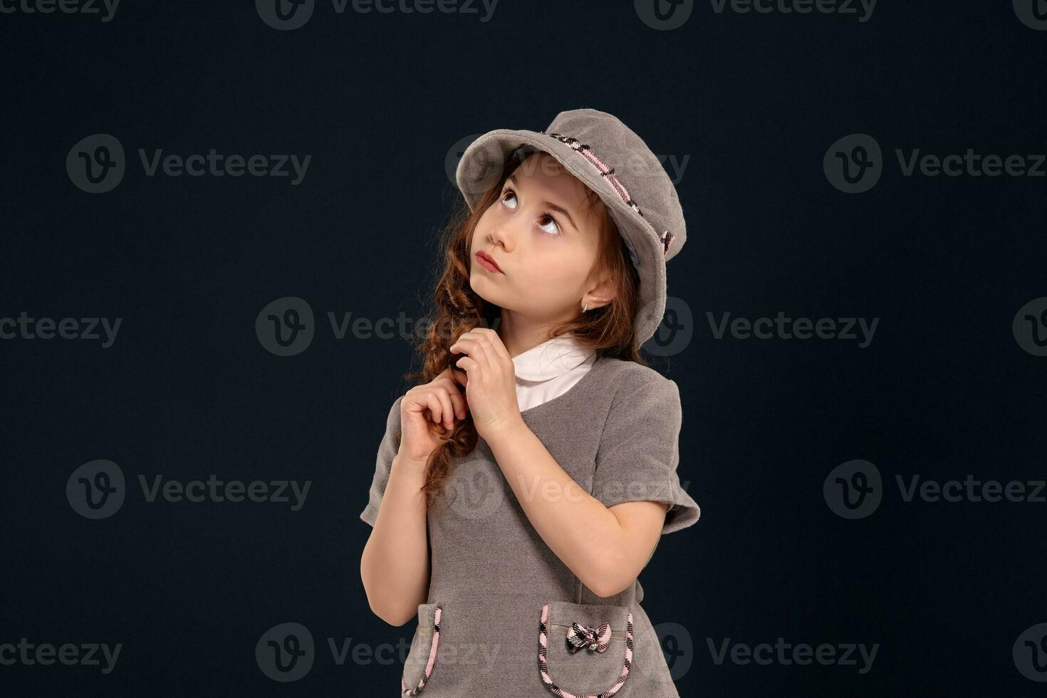 Studio shot of a lovely little kid with a long, curly hair posing on a black background. photo