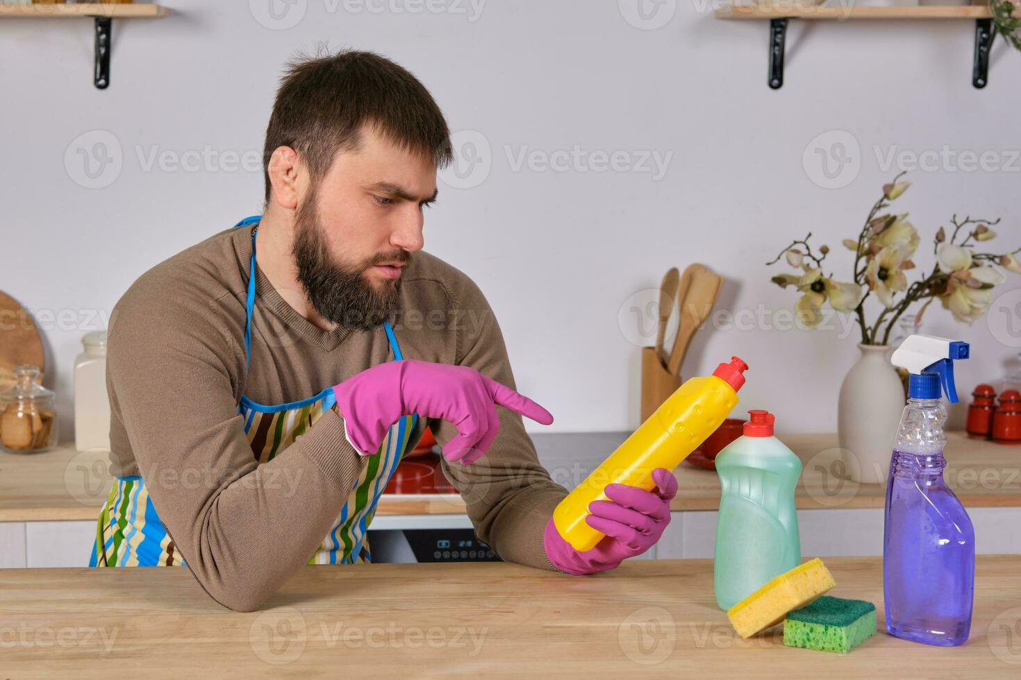 Young man wanted to help his wife in housecleaning, but he doesn't know what to do with all of detergents photo