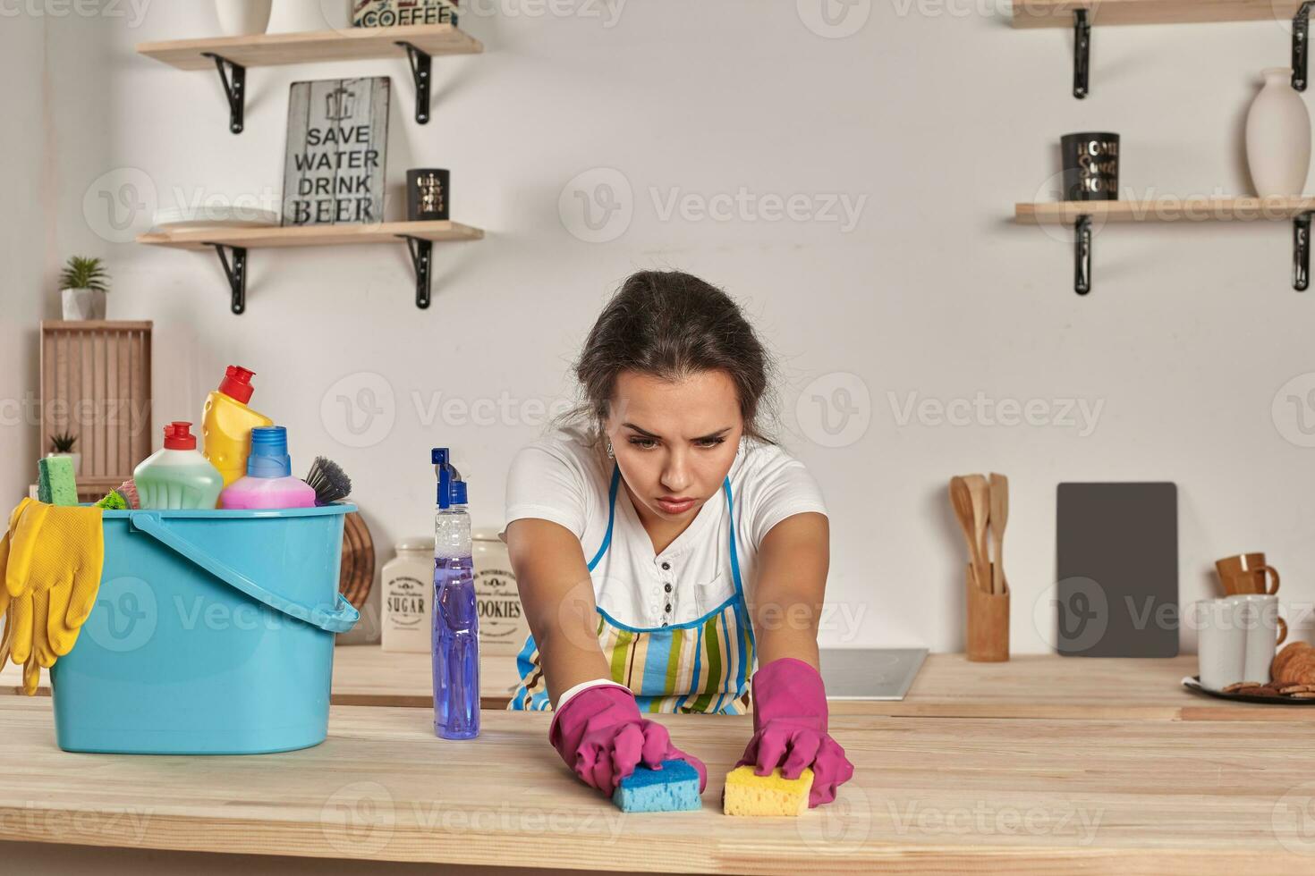 hermosa alegre morena mujer en guantes limpieza moderno cocina foto