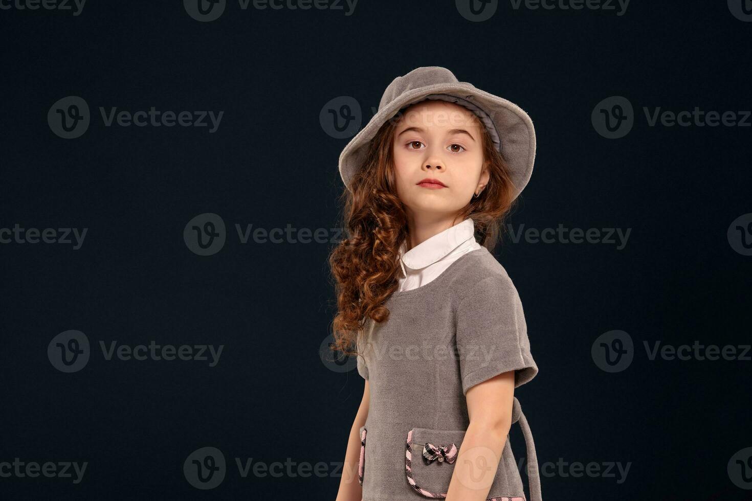 Studio shot of a lovely little kid with a long, curly hair posing on a black background. photo