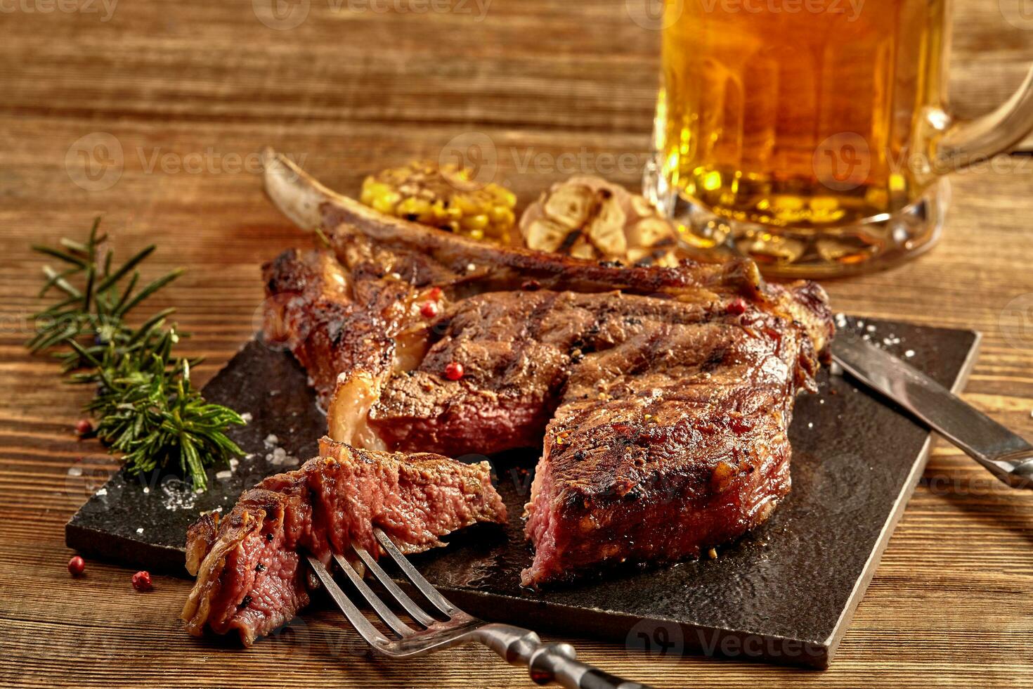 Grilled cowboy beef steak, glass of beer, herbs and spices on a wooden background. Top view. photo